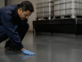 tecnico inspeccionando pavimento antiacido gris contenedores ibc nave industria quimica madrid